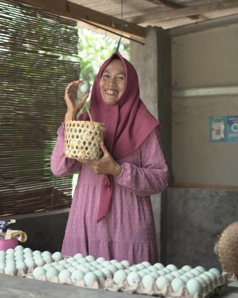 A vendor holding a basket of salted eggs for sale.