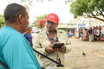 Mercy corps employee holding a tablet speaking to a man
