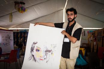 A young man holding a large painting of a girl's face