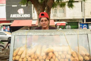 A person in a backwards red cap selling loaves of bread in colombia