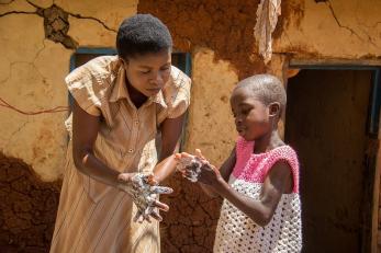 woman showing child how to wash hands