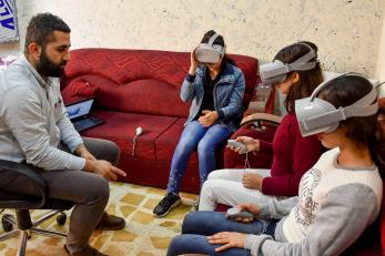 Young people sit on sofas while learning to use virtual reality equipment.