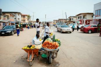 People selling fruits and vegetables on a busy street.