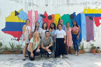 Mercy Corps Colombia team members and participants stand in front of a mural celebrating unity.