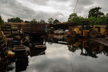 Damage construction equipment sits in a flooded business yard.