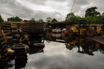 Damage construction equipment sits in a flooded business yard. 