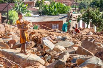 A young person carries debris from one of the many landslides that crisscross Ngangu in the aftermath of Cyclone Idai.