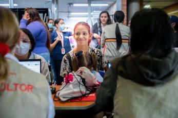 A person holding their child while speaking with Mercy Corps staff at a health clinic in Medellín, Colombia.