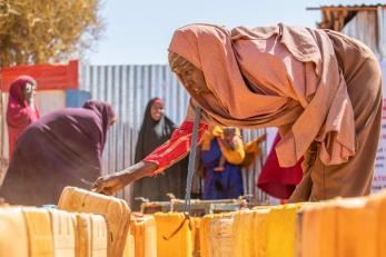 A person reaching for a jerry can at an internally displaced persons camp.