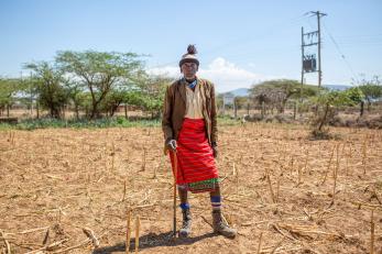 A pastoralist standing in a dry landscape.