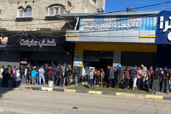 people standing in line outside of a bakery in Rafah