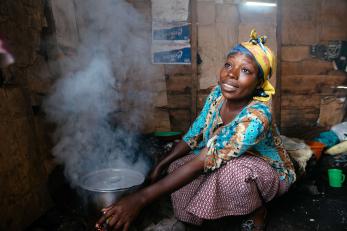 A person cooking in a one room hut.