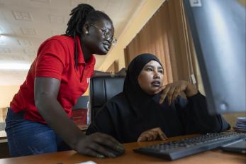 Two Kenyan women work in front of a computer together.