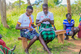 Young women sit on benches working together on program material.
