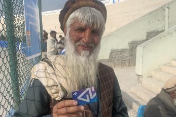 HesabPay user stands outside fenced area showing payment card.