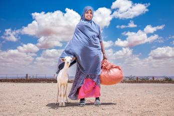 Ethiopian woman with her goat stand on the plains.