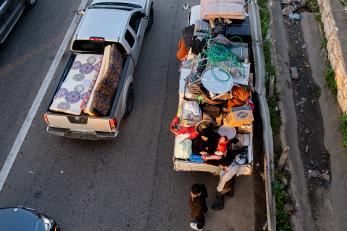 View from above as trucks loaded with personal items are waiting in traffic.
