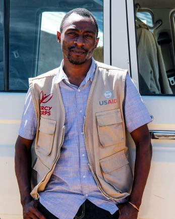 A Mercy Corps employee stands next to a vehicle