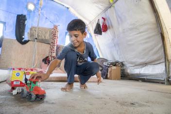 Mohammed, 10, plays with a toy truck that he made inside his family's tent at the Jeddah displacement camp. The toy is a humanitarian aid truck, he says, delivering supplies to the camp.