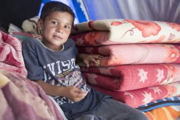 Yaser sits on blankets inside his family's tent at the Jeddah displacement camp. His family has been displaced since the beginning of the conflict when their home was completely destroyed. A kit with household essentials from Mercy Corps ensures his family has a few household items, as they weren’t able to bring anything with them when they fled the violence.