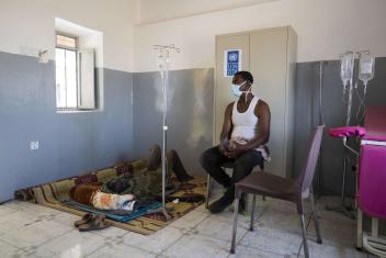 Adom Beyet, a patient at the Um Rakuba health centre, waits to see a doctor while another patient receives treatment.