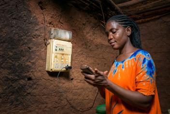 In rural Nandagala, Tanzania, a homeowner charges her phone at the ready board, a device with switches and sockets for houses to immediately use energy after connection.