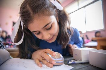 At an inclusive school in Zarqa, students with visual impairments like Noor use a magnifier to help with learning.