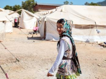 Girl in green scarf smiling at refugee camp