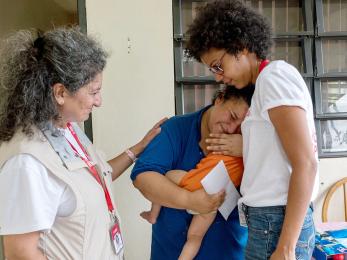 Mercy corps team members karla peña, right, and pardis barjesteh, comfort a crying stephanie, 27, after she received cash and a water filtration system from them. photo: angel valentin for mercy corps