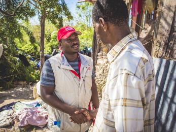 Mercy corps employee shaking hands with haitian hurricane victim