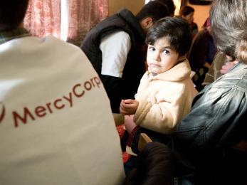 A small child in georgia next to a mercy corps team member