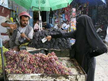 A person buys fruit at a market from a vendor.