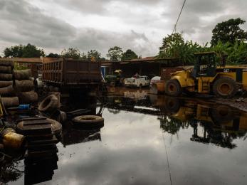 Damage construction equipment sits in a flooded business yard. 
