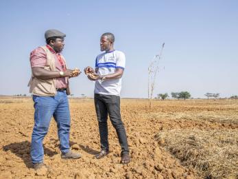 Two people having a conversation in a field.