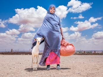 Ethiopian woman with her goat stand on the plains.