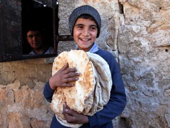 A young boy in syria holding fresh bread