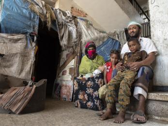 Yemeni family sitting together outside their home's entrance.