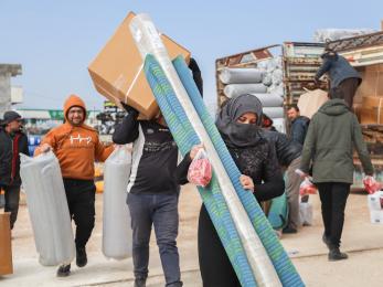 A woman in northwest syria carries emergency kits delivered by mercy corps.