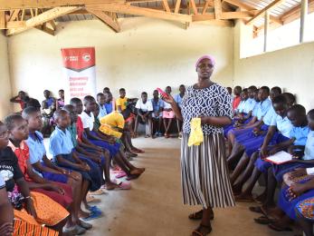 A person speaking to a room full of young people.