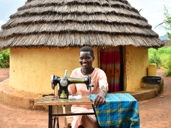A girl-h participant poses with a tailoring machine she purchased through her participation in the girl-h financial inclusion interventions.